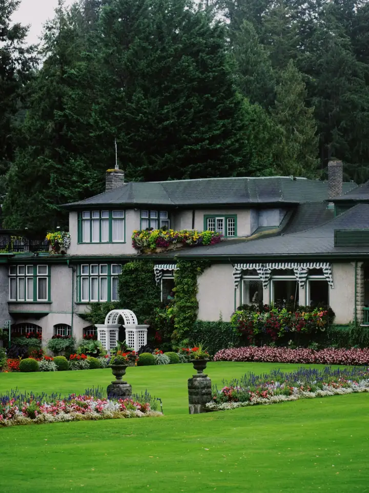 A house behind a green lawn and flower beds