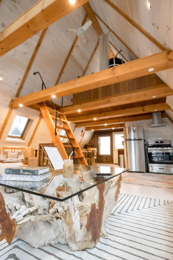 Bright A-frame cabin interior with a lounge area under exposed beams